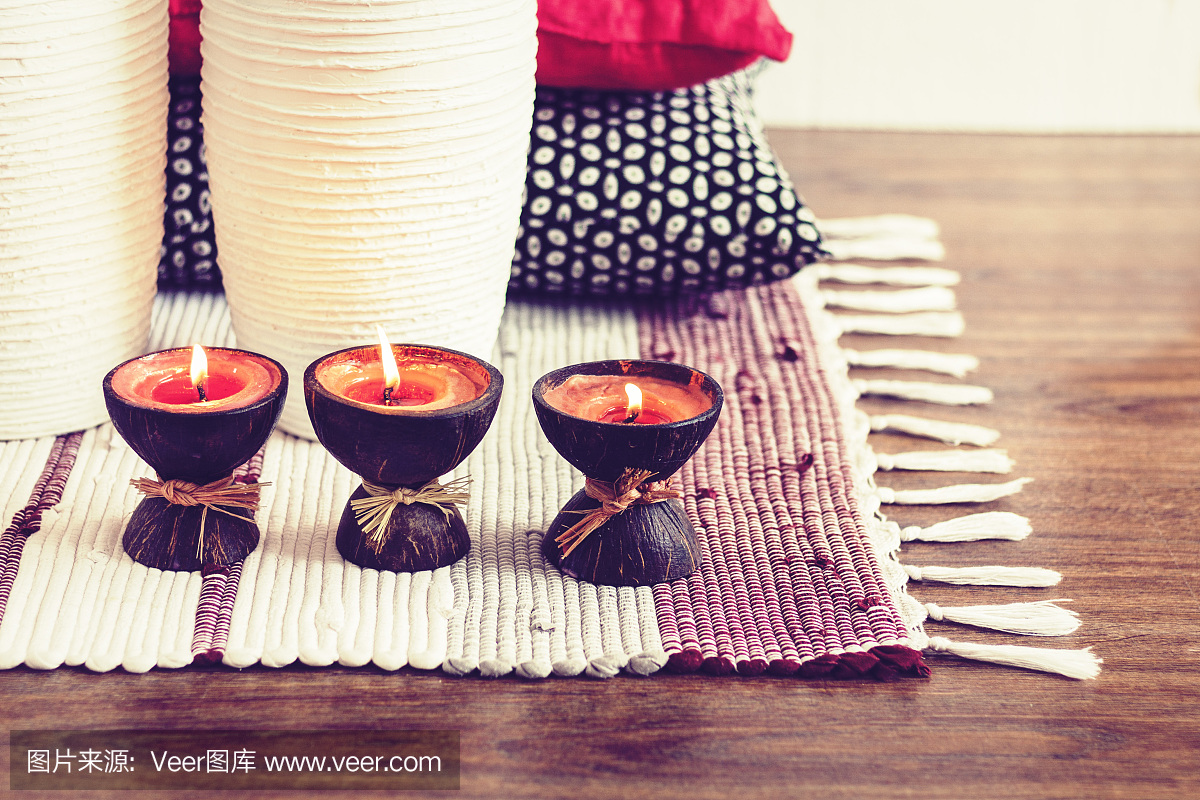 舒适的家庭室内装饰,燃烧的蜡烛在椰子壳上的多色地毯